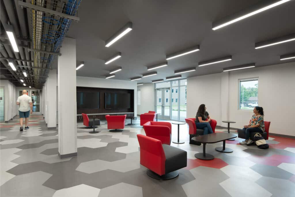 Modern office lounge with people and geometric carpet.